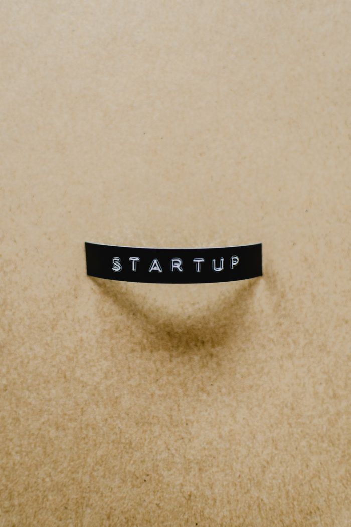 A minimalist image of the word STARTUP on a beige textured surface conveying creative business concepts.